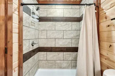 Full tub and tile shower — because when you're traveling with a crowd, every bathroom needs to pull its weight. This one does, with warm cabin walls and clean finishes.