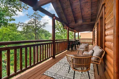 Covered deck wrapped in tree canopy — sip your morning coffee here while the Smokies wake up around you. Wicker seating, mountain air, zero agenda.