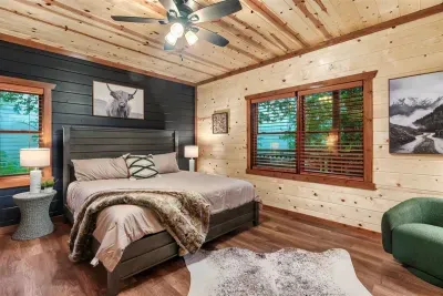 King bedroom with a navy accent wall, fur throw, and elk art overhead — bold mountain lodge design that makes this room feel like a destination, not just a place to sleep.