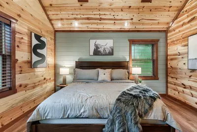 Handsome king suite with warm cabin walls, curated art, and moody amber lighting — the kind of room you don't want to leave in the morning.
