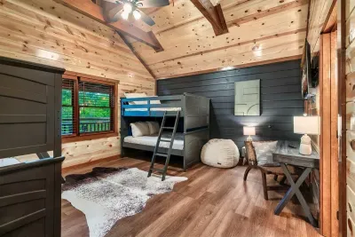 Navy accent bunk room with twin-over-full beds, a bean bag landing zone, and vaulted pine overhead — the kids will claim this room before you finish unpacking.