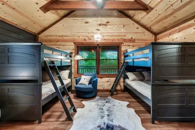 Dedicated bunk room with two sets of full-over-full beds — the kids claim it every time. Wood-vaulted ceiling, hardwood floors, and cowhide rug included.