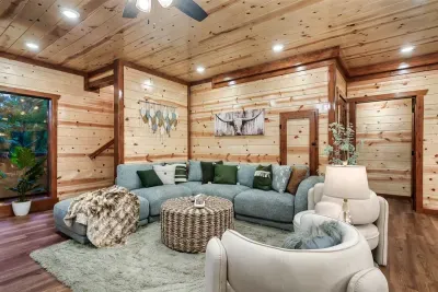 Curved white sectional, longhorn art, and layered cabin textures — a living room that leans into mountain lodge design without sacrificing an ounce of comfort.