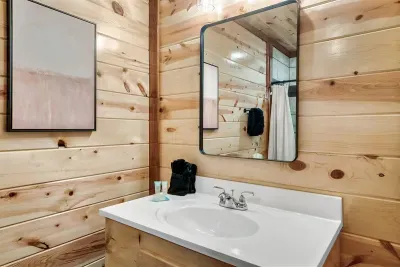 Light, clean, and well-appointed — this wood-paneled vanity bathroom keeps the cabin character while delivering the polished finish your group expects.
