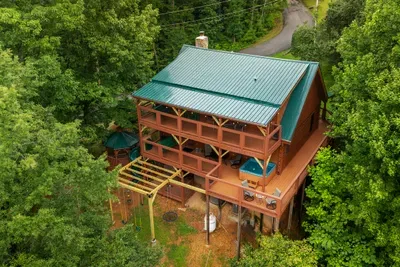 Green-roofed log cabin tucked into unbroken forest. Private, quiet, and closer to Dollywood and the Parkway than the drive up here makes it feel.