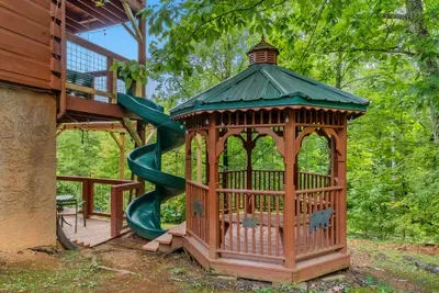 A cedar gazebo tucked into the woods with a spiral slide spilling off the side. Part playhouse, part hideout — kids disappear into it for hours.