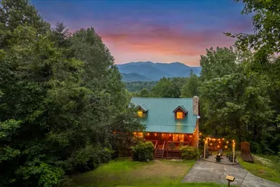 Cabin glowing at sunset with the ridge line turning pink behind it. This is the drive-up view on your first night, and it doesn't get old.