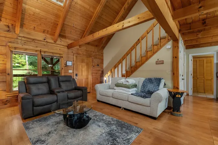 Soaring beams, an open staircase, and light pouring through the trees. Vaulted living space that makes a log cabin feel wide open instead of closed in.