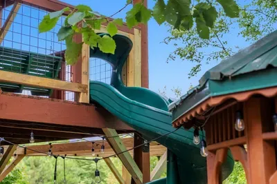The spiral slide off the upper deck — the fastest route from porch to yard. Kids find it in the first five minutes and use it all weekend long.