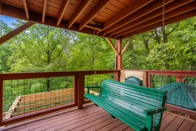 Deck bench looking out over the treetops. Coffee at sunrise, a book at noon, cool mountain air moving through the whole time you're sitting there.