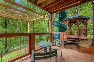Covered deck with cafe seating looking straight at the gazebo and slide. Watch the kids play from a chair with your coffee still hot.