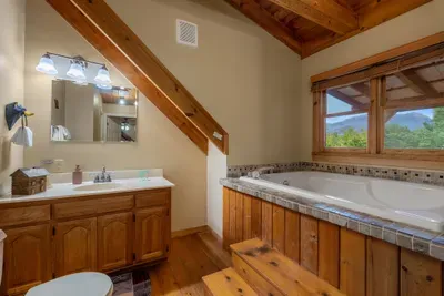 Corner soaking tub under a vaulted ceiling with a full vanity beside it. Fill it, sink in, and let the hot water finish what the hiking trail started today.