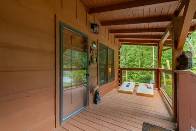 Covered porch with cornhole set up and out of the rain. Play a round while dinner's on the grill — the forecast doesn't cancel anything here.