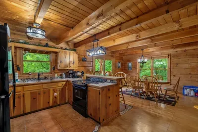 Open kitchen with bar seating and windows to the woods. Everything you need to cook in and skip the ninety-minute restaurant wait in Pigeon Forge tonight.