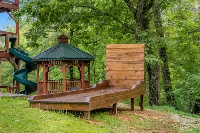 Gazebo, spiral slide, and a wooden ramp running back to the cabin. A private play structure in the trees, all yours for the length of the stay.