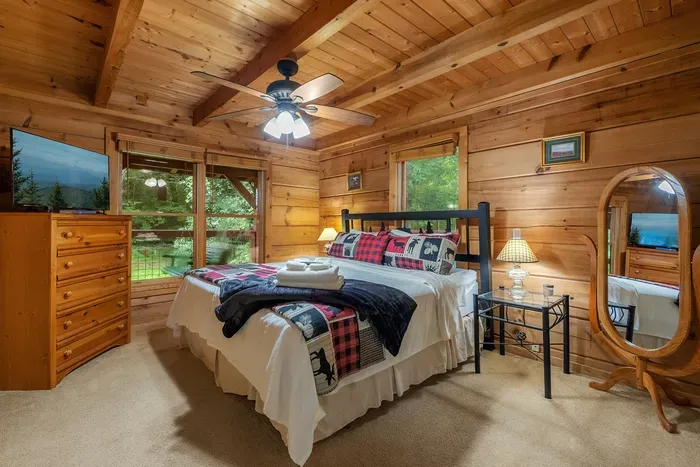 Log walls, a mountain quilt, and a window to the trees. Room to actually unpack — a bedroom that feels like a retreat, not just a place to drop the bags.