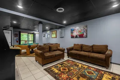 Lower-level rec room with deep sofas and a big screen. Where the second half of the group settles in — two living areas means nobody fights over the TV.
