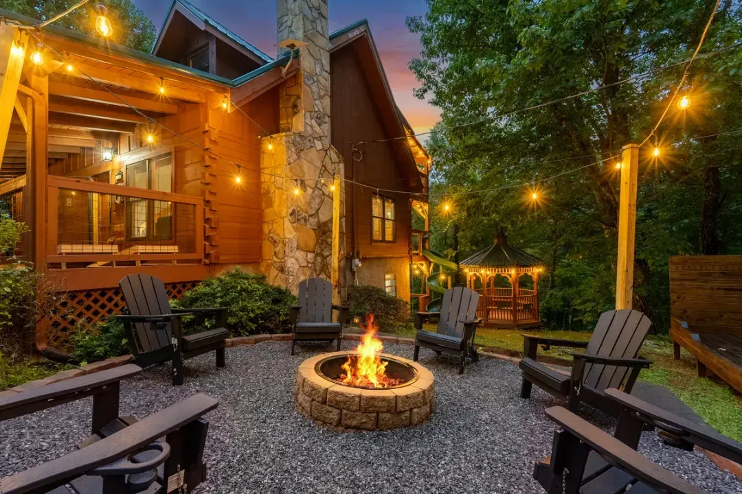 Fire pit burning at dusk with chairs pulled in close and string lights overhead. The gathering spot every night, no matter what the day's plan was.
