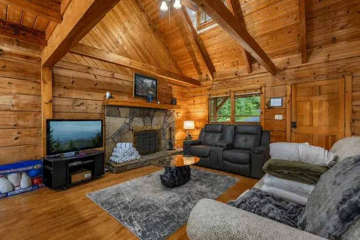 Spacious living room with vaulted ceilings, cozy seating, a Smart TV, and a charming decorative stone fireplace. Perfect for relaxing after a day in the Smokies.