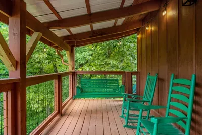 Green rocking chairs lined up on the covered porch, forest pressing in. Rock, listen, and let the mountain morning take exactly as long as it wants.