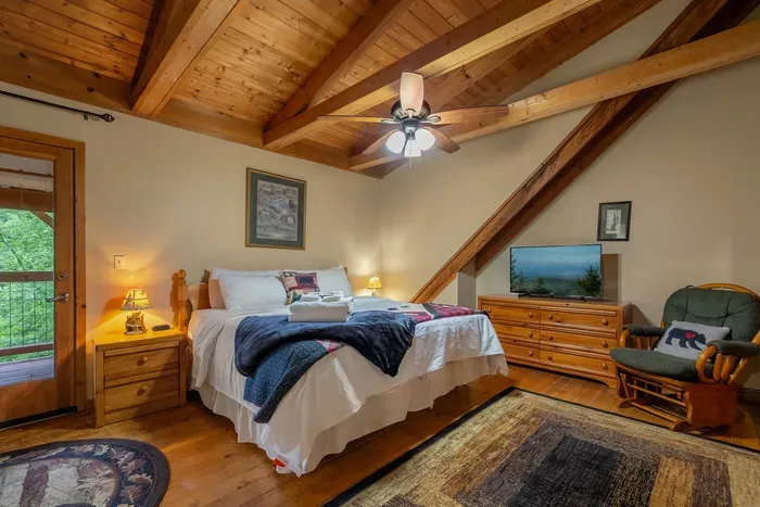 Vaulted wood ceilings, a quilted bed, and a ceiling fan turning slow. Windows full of green and the kind of mountain quiet that puts you out by nine.