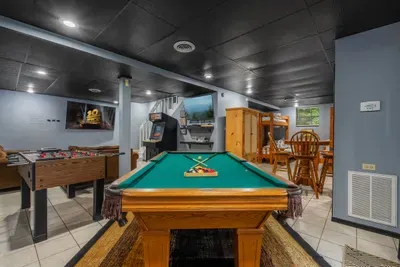 Pool table, dartboard, and big screen in the lower-level game room. Where the tournament starts after dinner and somehow keeps running until well past everyone's bedtime.