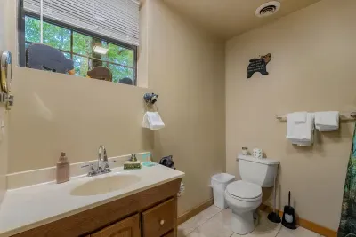 Window-lit bath with a full vanity and towels stacked and ready. Multiple bathrooms across the cabin means no morning bottleneck for a large group.