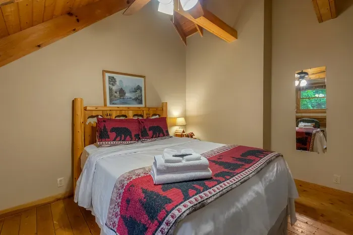 Cabin quilts, wood-paneled walls, and towels rolled and waiting. One of several bedrooms, so a big group sleeps in real beds instead of on the pull-out.