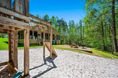 Community playground with a view of picnic tables and charcoal grill.