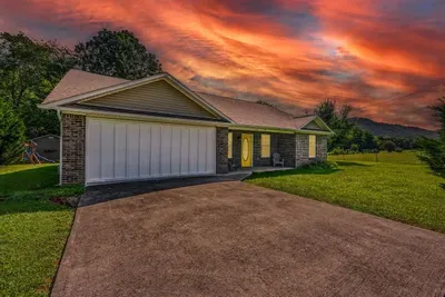 Brick exterior, two-car garage, mountain backdrop, and a kids' playset tucked in the yard — your home base arrives with more than you expected, right from the driveway.