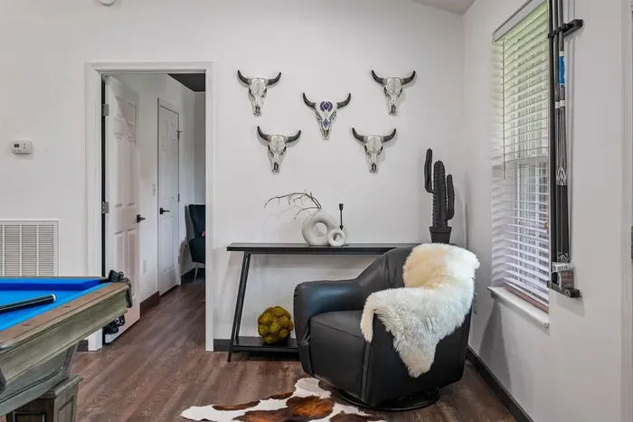 Tucked beside the pool table — a leather swivel chair, sheepskin throw, cowhide rug, and a gallery of longhorn mounts that make this game room feel like no one else's.