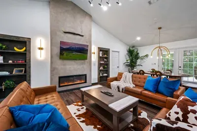 Vaulted ceilings, a sleek linear fireplace, tufted leather sofas, and a cowhide rug — the main living room sets a tone that says this cabin is anything but ordinary.
