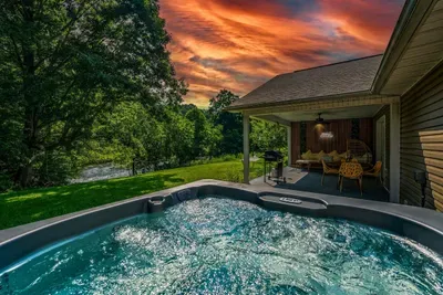 Soak in the private hot tub as the sky ignites above the Pigeon River — then drift to the covered patio, grill, and hanging chair. Evenings don't get better than this.