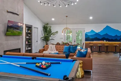 Full game room with pool table, handcrafted bar, and a floor-to-ceiling mountain mural — the after-dark hangout spot your group will never want to leave.
