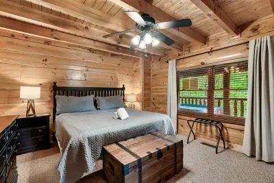 A spacious king bedroom designed for rest — plush bedding, warm wood walls, and peaceful views right outside your window.