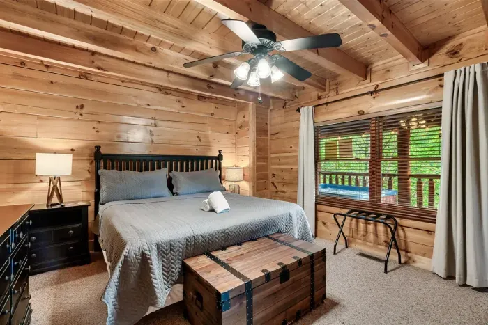 A spacious king bedroom designed for rest — plush bedding, warm wood walls, and peaceful views right outside your window.