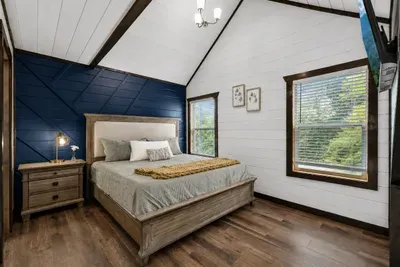 Bright king bedroom with cabin character and wooded views just outside the windows.