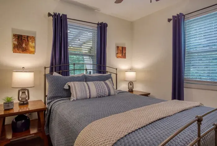 Queen bed, blackout curtains, and a window that opens to nothing but trees. Reading lamps on both nightstands and a quiet so complete you'll sleep past your alarm