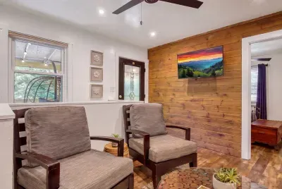 Pine accent wall, mountain art, and armchairs angled toward the windows. Sunlight all afternoon, and a second living space so the group can spread out.