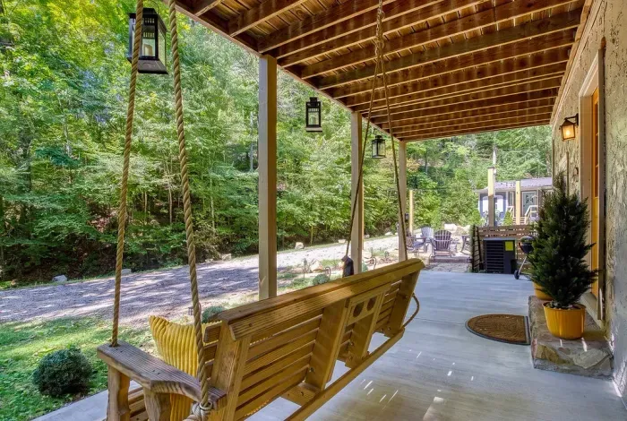 A covered porch swing facing nothing but green — lantern light overhead, mountain air moving through, and the kind of slow afternoon you drove all this way to find. Guests claim this spot first.