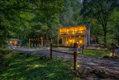 Pull up after dark and the cabin's already glowing for you — lit windows, string lights, and the woods going quiet. That first look never gets old.