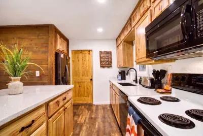 Full-size fridge, range, and microwave tucked into warm knotty-pine cabinets. Load up in town, unpack once, and cook every meal here without missing a thing from home.