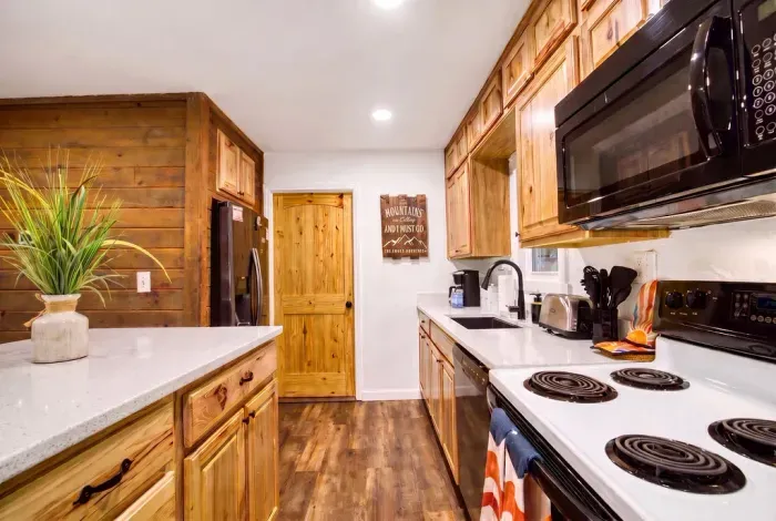 Full-size fridge, range, and microwave tucked into warm knotty-pine cabinets. Load up in town, unpack once, and cook every meal here without missing a thing from home.