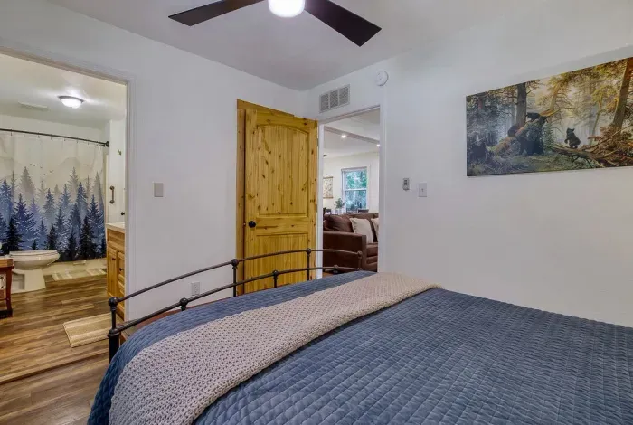 Upstairs bedroom with the bath steps away and a loft railing overlooking the great room below. Cool, quiet, and tucked away — the room everyone quietly hopes they get.