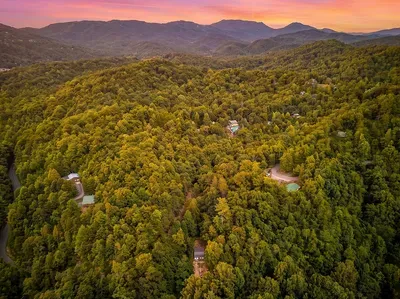 Tucked into acres of hardwood forest with the ridgelines rolling out behind — that's your cabin down there, private and quiet, with the mountains starting at your doorstep.