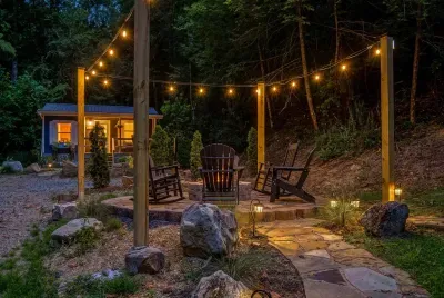 Stone fire pit ringed in rocking chairs, string lights overhead, forest dark beyond. Bring the s'mores — this is where the stories run long and nobody checks their phone.