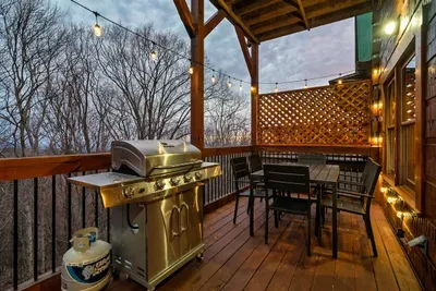 Main floor deck has a propane gas grill, hanging light bulbs, and seating for six people