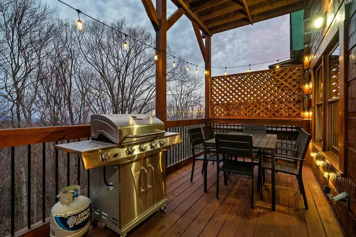 Main floor deck has a propane gas grill, hanging light bulbs, and seating for six people
