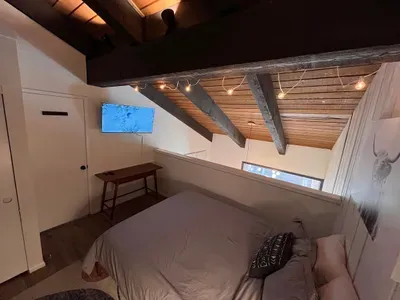 Loft view of queen bed, 40" smart TV and door leading to the upstairs hallway.