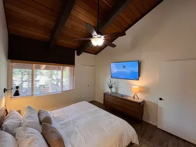 Bedroom with a king bed, cealing fan, 65" smart TV and a beautiful view of the Sherwins.